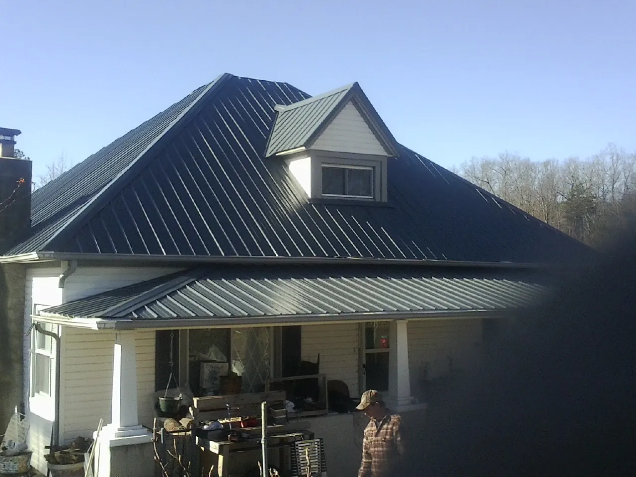 Dark blue standing seam metal roof with a dormer above a front porch in Creola