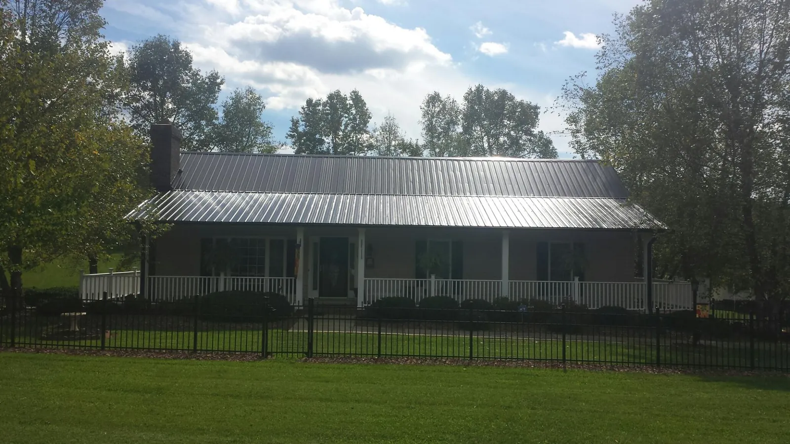 Gray metal roof on a brick ranch with a full width front porch — Gutter Guard Installation work by our crew in Creola