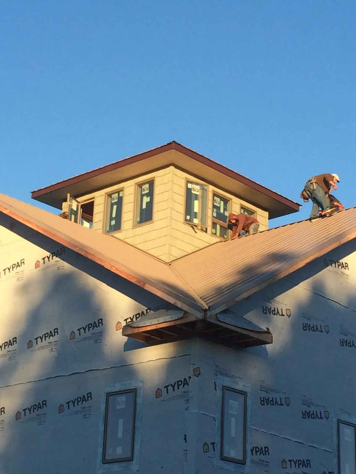 Roofers working around a rooftop cupola on a new metal roof at sunset — Roof Waterproofing in Creola by Roofing Brothers